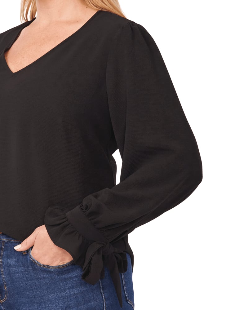 Side of a model wearing a size 1X Isla Tie-Sleeve Blouse in 060-RICH BLACK by CeCe. | dia_product_style_image_id:263558